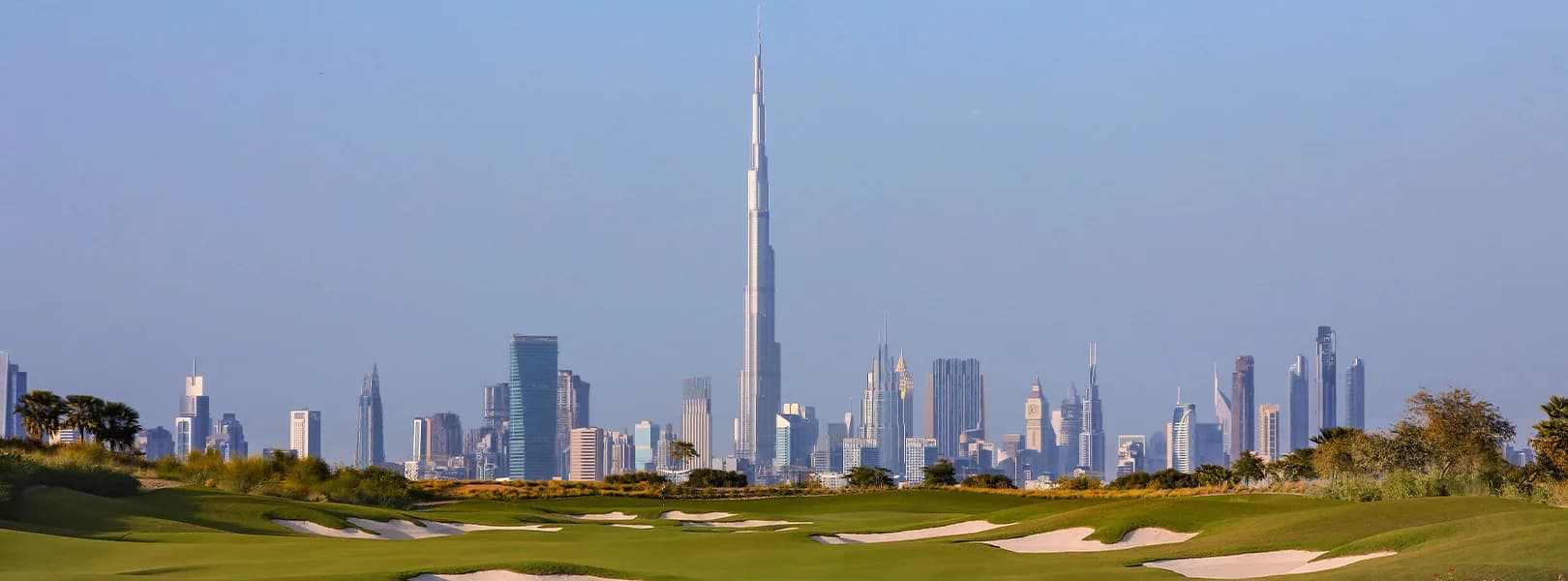 The Dubai Hills Golf Club fairway at ground level with the Dubai skyline beyond